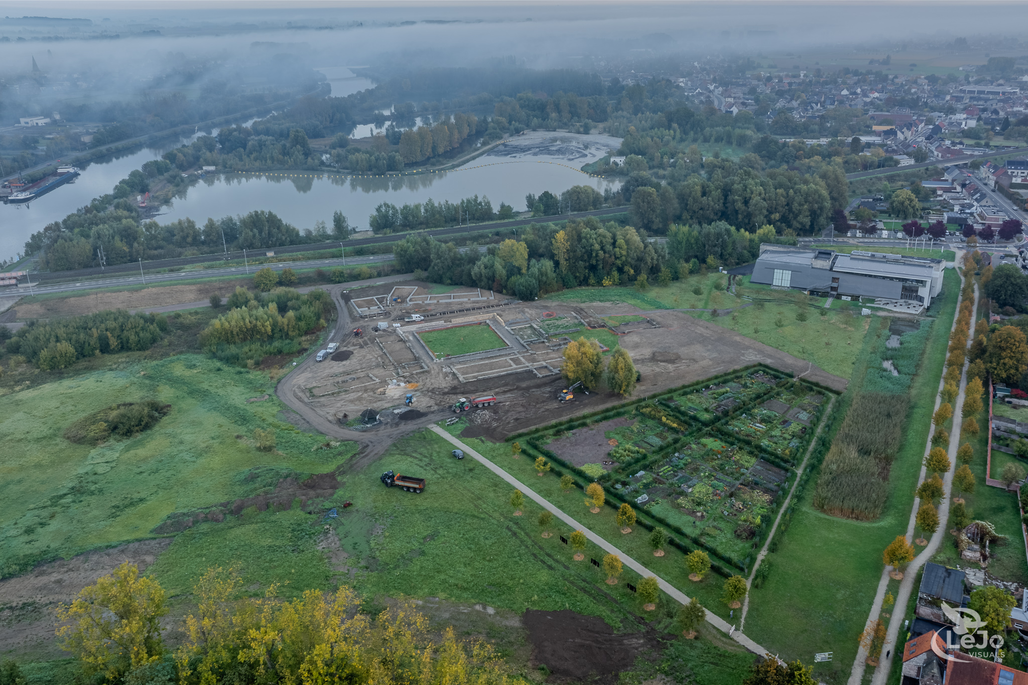 Dronefoto van de Archeosite Ename en de omliggende Scheldevallei tijdens zonsopkomst